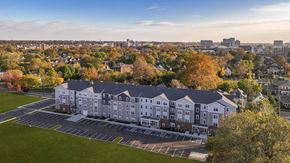 Cleveland apartment for rent - Aerial view of a modern apartment building surrounded by mature trees, open green space, and a vibrant neighborhood setting.