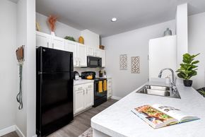Cleveland apartment for rent - Bright modern kitchen with white cabinetry, spacious countertops, black appliances, and a large center island for everyday living and dining.