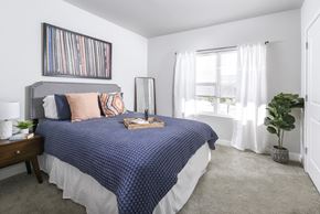 Cleveland apartment for rent - Bright bedroom with plush carpeting, modern furnishings, and a large window that fills the space with natural light.