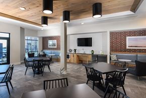 Austin apartment for rent - Resident clubhouse featuring dining tables, lounge seating, and a kitchenette for gatherings and community events.