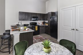 Mckinney apartment for rent - A kitchen with black cabinets and a marble countertop.