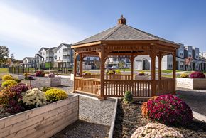 Saratoga Springs apartment for rent - Resident outdoor area with a shaded gazebo, garden planters, and a landscaped setting for relaxation and gathering.