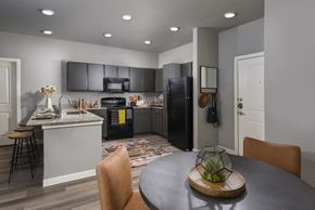 Austin apartment for rent - A modern kitchen with a black refrigerator and a dining table with chairs.