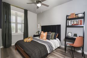 Austin apartment for rent - A bedroom with a bed, chair, and a fan.