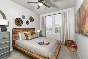 San Antonio apartment for rent - A bedroom with a bed, a dresser, and a painting on the wall.
