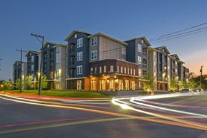San Antonio apartment for rent - A long exposure shot of a modern apartment building at dusk with light trails from moving vehicles.