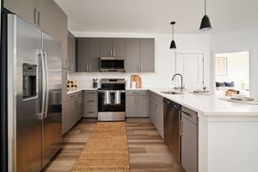 Austin apartment for rent - A modern kitchen with a refrigerator on the left and a sink on the right.