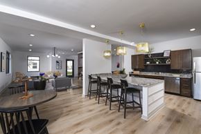 Columbus apartment for rent - Modern kitchen with a large island, granite-style countertops, bar seating, and stainless steel appliances in an open-concept layout.