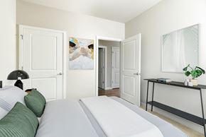 Selkirk apartment for rent - A bedroom with a white bed and a black shelf.