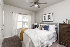 Charlotte apartment for rent - A bedroom with a white bed and a ceiling fan.