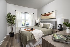 Saratoga Springs apartment for rent - Bright bedroom with a large window, soft curtains, and a neatly styled bed with neutral bedding and accent pillows.