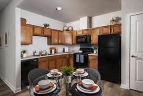 Saratoga Springs apartment for rent - Contemporary kitchen with ample cabinetry, black appliances, and an adjacent dining space with seating for four.