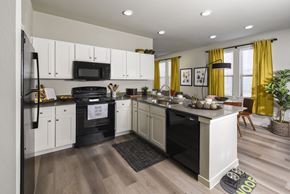 Converse apartment for rent - A modern kitchen with white cabinets and a black stove top oven.
