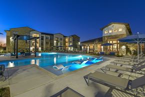 Converse apartment for rent - A swimming pool surrounded by lounge chairs and umbrellas at a resort.
