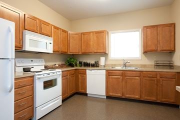Evansville apartment for rent - A kitchen with brown cabinets and white appliances.