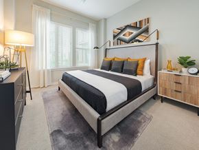 Houston apartment for rent - A bedroom with a large bed and a nightstand with a lamp.