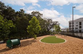 Kissimmee apartment for rent - A playground with a green tree and a brown sandy area.