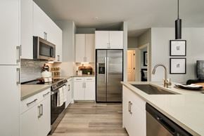 Houston apartment for rent - A modern kitchen with white cabinets and stainless steel appliances.