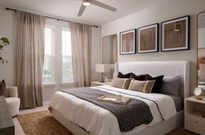 Fort Myers apartment for rent - A bedroom with a large bed, a ceiling fan, and a chair.