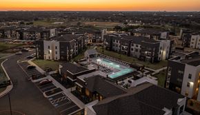 Killeen apartment for rent - an aerial view of an apartment complex with a pool at dusk