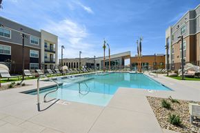 Las Vegas apartment for rent - A large swimming pool surrounded by lounge chairs and buildings.