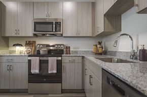 Sherman apartment for rent - A modern kitchen with a stove top oven and a microwave above it.