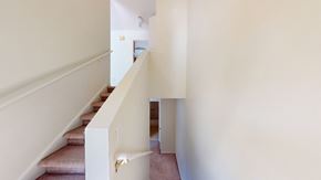 Ann Arbor triplex for rent - A staircase with a white railing and beige carpeted steps.