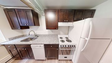 Ann Arbor apartment for rent - A kitchen with white appliances and brown cabinets.