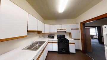 Ann Arbor apartment for rent - A modern kitchen with white cabinets and a black stove top oven.
