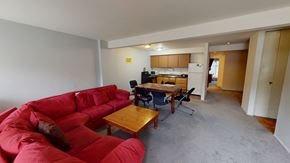 Ann Arbor apartment for rent - A red couch sits in a living room with a dining table and chairs.