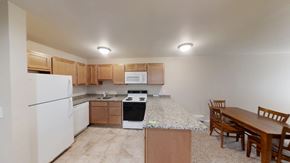 Ann Arbor apartment for rent - A kitchen with a white refrigerator, a white microwave, a black stove, wooden cabinets, and a wooden dining table.