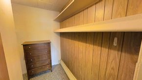 Ann Arbor apartment for rent - A wooden dresser sits in a room with a white wall and a wooden shelf above it.