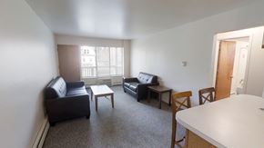 Ann Arbor apartment for rent - A living room with a black couch, a black chair, a white table, and a brown chair.