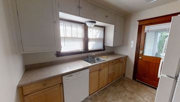 Ann Arbor house for rent - A kitchen with a white dishwasher and wooden cabinets.