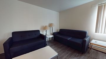 Ann Arbor apartment for rent - Two black couches in a living room with a white table and a lamp.