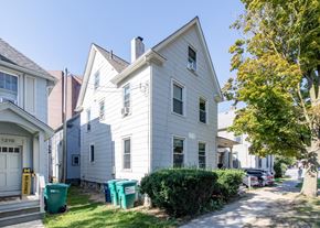 Ann Arbor apartment for rent - A white house with a green trash can in front of it.