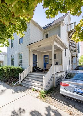 Ann Arbor apartment for rent - A white house with a blue door and a car parked in front.