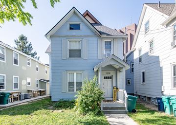 Ann Arbor apartment for rent - A blue house with a white door and windows is in front of other houses.