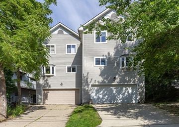 Ann Arbor triplex for rent - A two-story house with a garage is surrounded by trees.