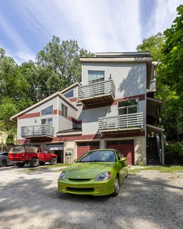 Ann Arbor apartment for rent - A green car is parked in front of a two-story house.