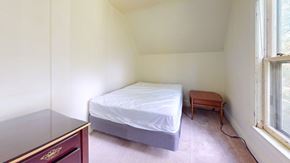 Ann Arbor apartment for rent - A bedroom with a bed, a small table, and a window.