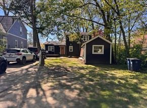 Ann Arbor apartment for rent - A small black house with a red door is surrounded by trees and a white car is parked in the driveway.