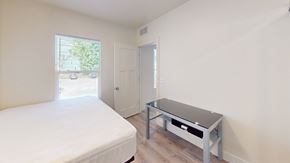 Ann Arbor apartment for rent - A bedroom with a bed, a table, and a window.