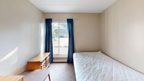 Ann Arbor apartment for rent - A bedroom with a bed, nightstand, and window with blue curtains.