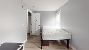 Ann Arbor apartment for rent - A bedroom with a bed, nightstand, and a window.