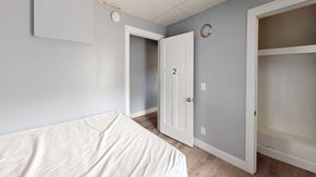 Ann Arbor apartment for rent - A white bed with a white sheet on it in a room with a white door and a white wall.