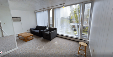 Ann Arbor apartment for rent - A living room with a black couch and a wooden stool.