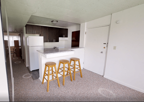 Ann Arbor apartment for rent - A kitchen with a white fridge and wooden stools.