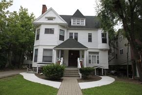 Ann Arbor apartment for rent - A white Victorian style house with a black roof and a brick walkway leading to the front door.
