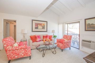 Buena Park apartment for rent - A living room with a red floral patterned chair and a glass coffee table.